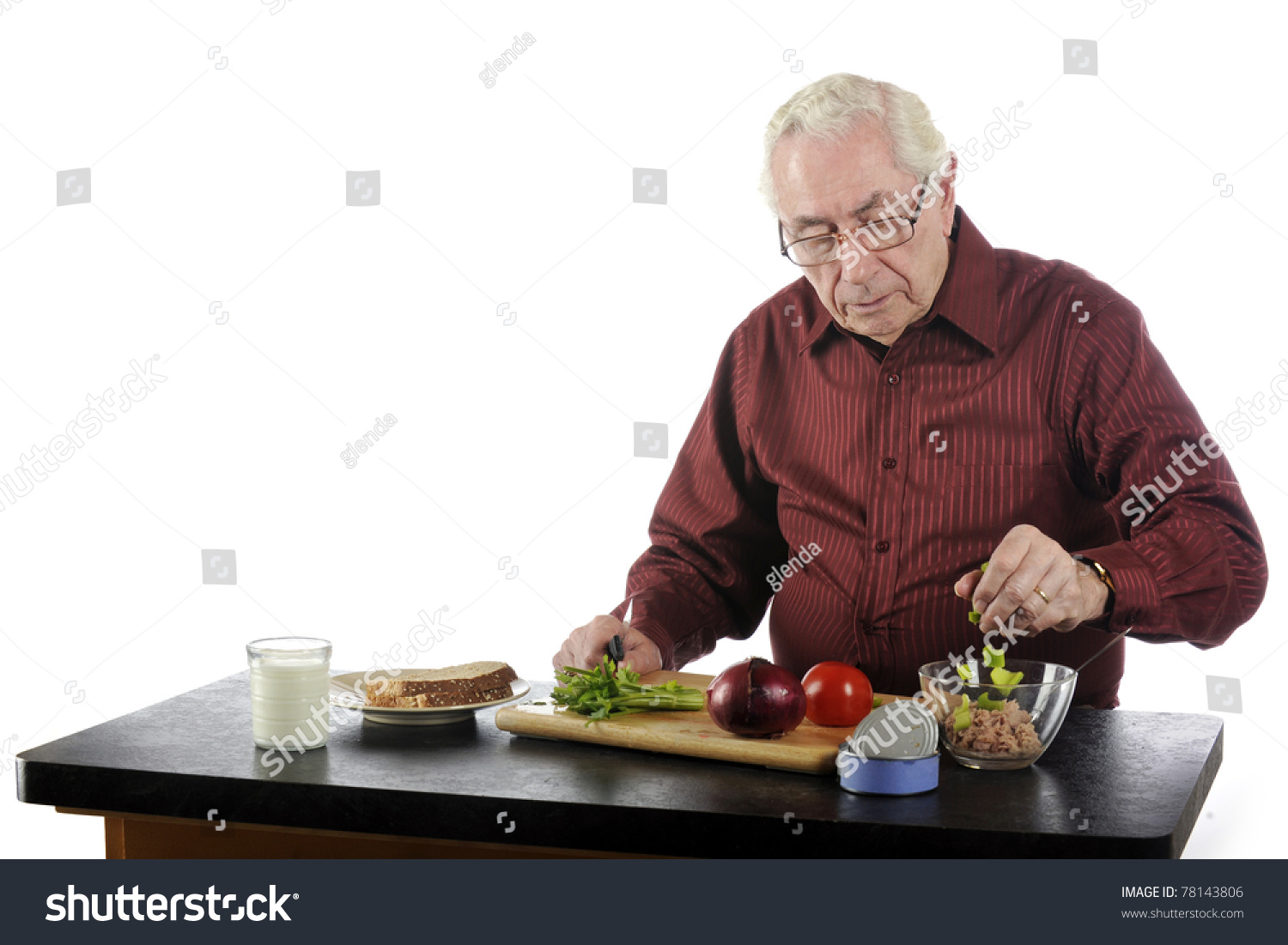 一位老人在一个温和的玻璃杯中准备午餐三明治