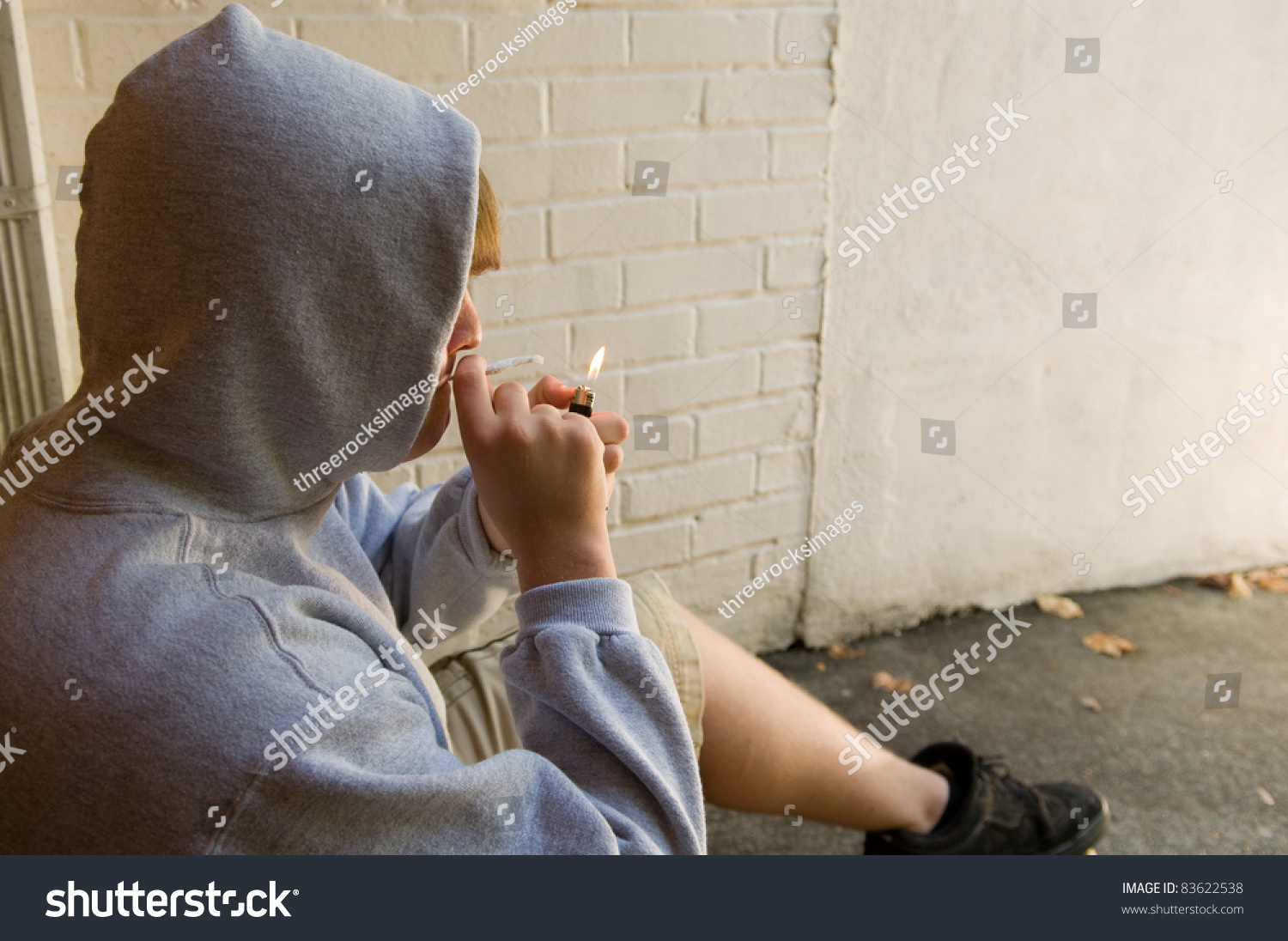 十几岁的男孩在脏的城市设置照明大麻香烟-医