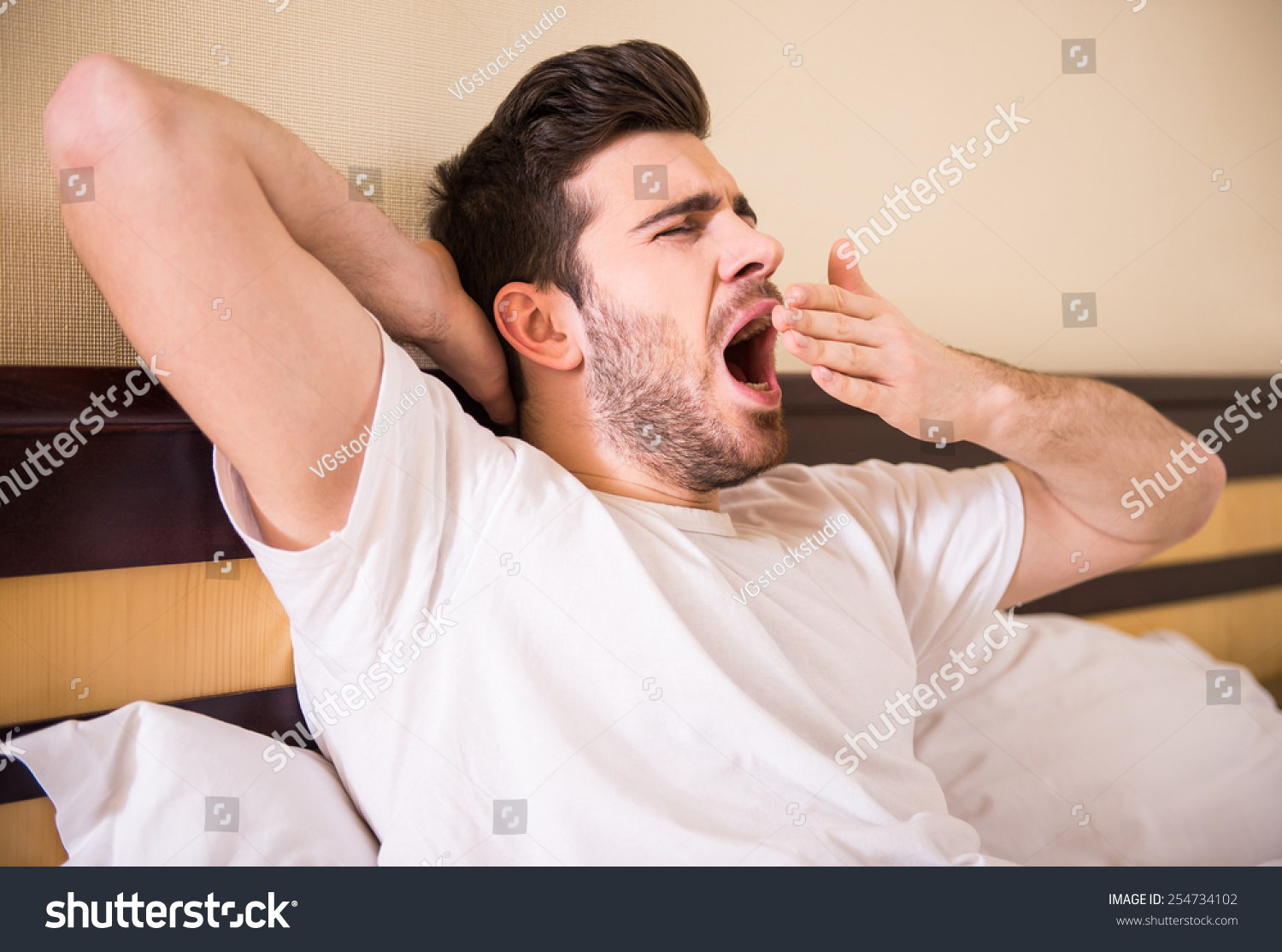 attractive guy is stretching and yawning in bed.